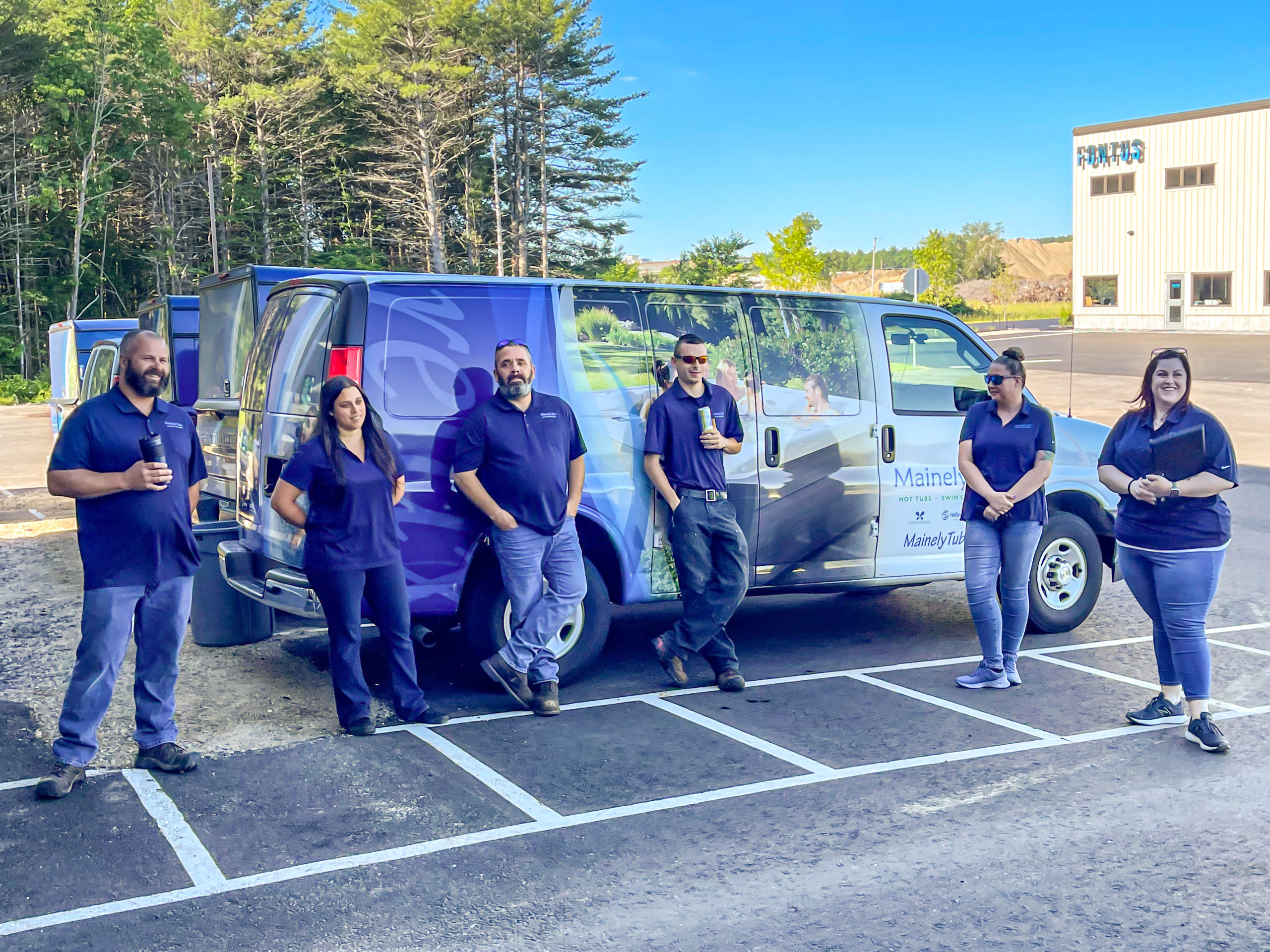 A group of service technicians standing in front of a service tech van outside of the warehouse.