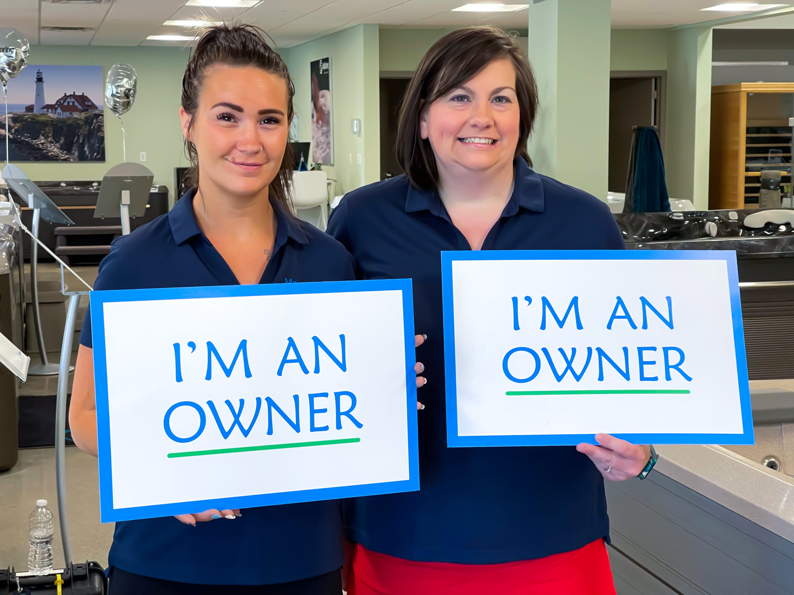 Two females holding 'I'm an owner' signs inside the Scarborough showroom.