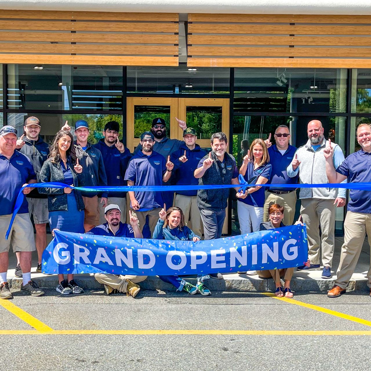 Mainely Tubs staff outside of their Hanover, MA showroom holding a grand opening sign.